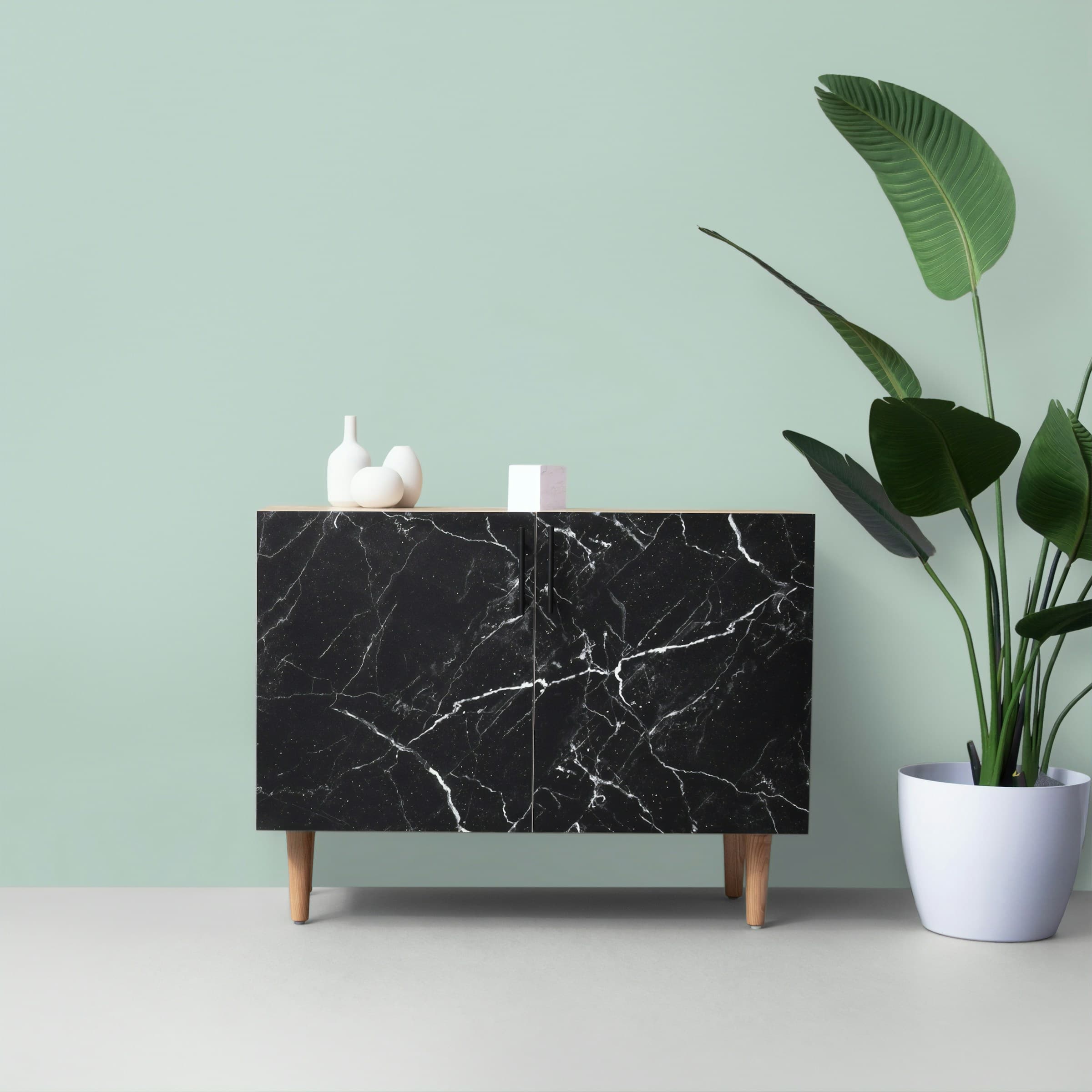 A dressor with a plant beside it